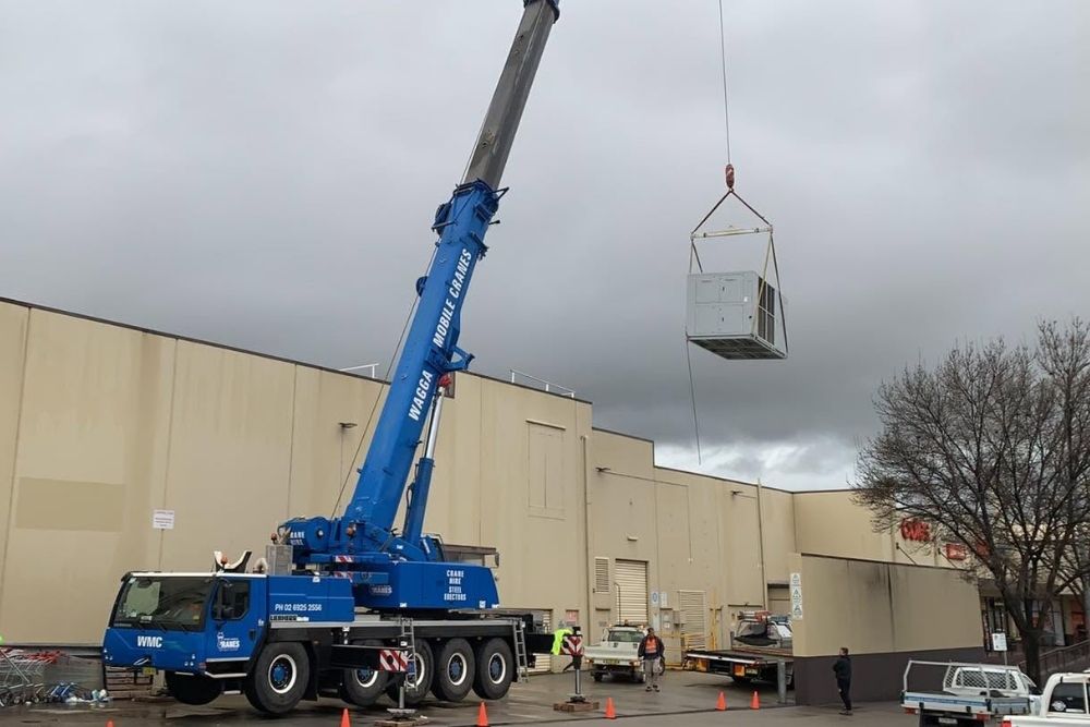 Large crane lifting an HVAC unit onto a shopping centre roof